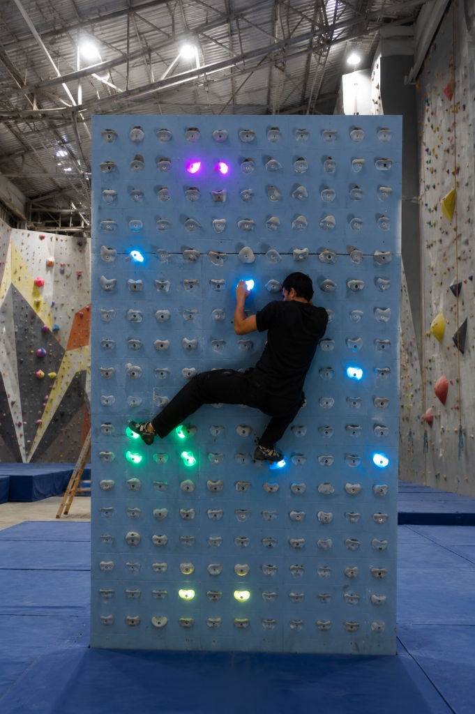 Climber on the ClimbFit interactive wall with illuminated multi-color LED holds